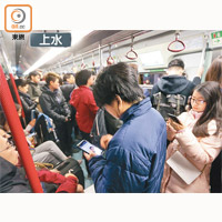 停駛的列車內人頭湧湧，乘客玩手機打發時間。
