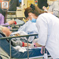 伊院急症室擠迫，護士在大堂替擔架床上的病人抽血。（黃雄攝）