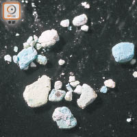 濾水器隔網上積存的藍白色顆粒，大小不一。（黃仲民攝）