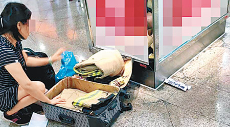 女水貨客蹲在商場地上整理行李箱，內疑有消防處所用的「黃金戰衣」。（互聯網圖片）