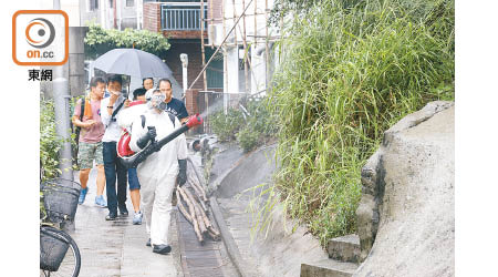 食環署人員在小路旁雜草區噴滅蚊藥。（陳章存攝）