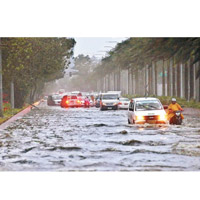 暴雨令多條道路水浸，汽車需涉水而行。（美聯社圖片）