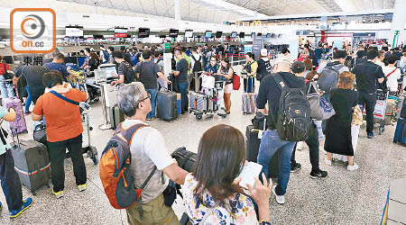 大批旅客在機場等候航班最新消息。（羅錦鴻攝）