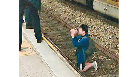 少年跪在路軌，雙手合十。（互聯網圖片）