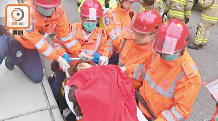受傷女乘客由救護員抬上擔架送院，神情痛苦。