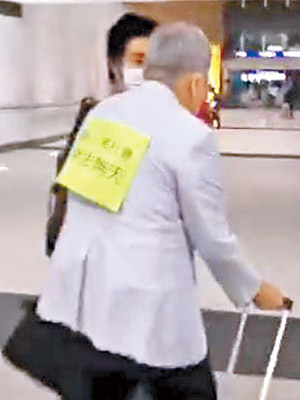 老翁背後被人張貼一大張黃色標語。（互聯網圖片）