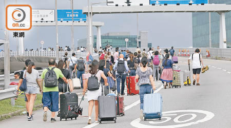 因交通受阻，大批旅客及機組人員要由東涌徒步行至機場。（袁志豪攝）