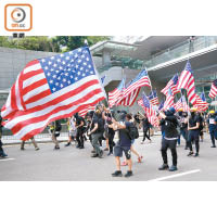大批示威者在遊行期間，揮動美國國旗。（李華輝攝）