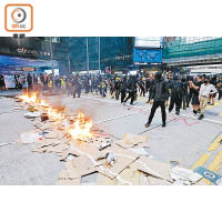 示威者在畢打街築起防線，燃燒鋪在地上的紙皮。