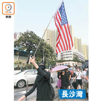 遊行隊伍中有示威者高舉美國國旗。