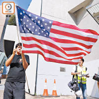 政府發表新一份施政報告，有人持美國國旗到政府總部外抗議。（何天成攝）
