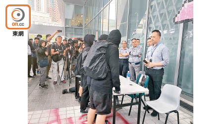 身穿黑衣的蒙面人士昨到香港知專設計學院圍堵院長王麗蓮，質疑校方隱瞞陳彥霖失蹤的閉路電視片段。（葉子健攝）