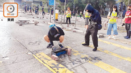 示威者用物件堵路，地上噴有「炸彈勿動」字眼。（曾紹良攝）