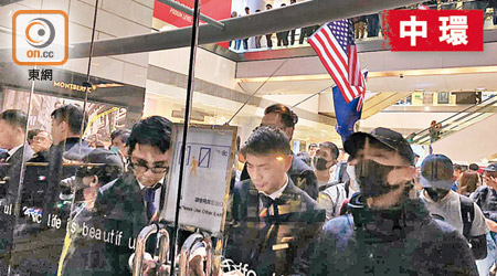 大批示威者在國金商場內聚集，有人高舉美國旗。（區慧盈攝）