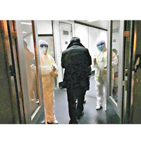 北京機場人員穿上保護衣，為來自武漢的乘客量度體溫。（美聯社圖片）