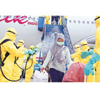 印尼僑民飛返祖國，落機時接受消毒。（美聯社圖片）