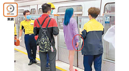 戴藍色髮帶（紅圈示）女子在等候列車。