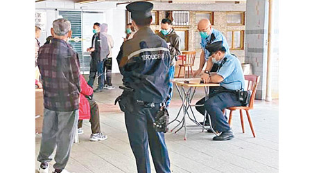 沙角邨<br>警方在沙角邨票控十三人違反禁聚令，有警員在場登記資料。