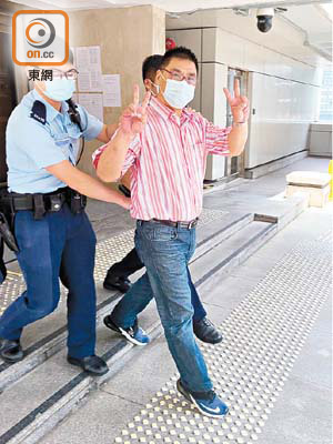 涉嫌偷錄法庭聆訊的印尼漢被警方帶走時狀甚「得戚」。（溫卓賢攝）