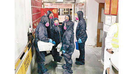6名穿深藍色全身保護衣人士，持消毒劑噴灑器候命。