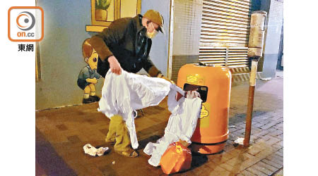 一名長者徒手將保護衣翻出垃圾桶外。（朱先儒攝）