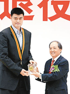 國家體育總局副局長肖天（右），為姚明頒發榮譽獎章。（中新社圖片）