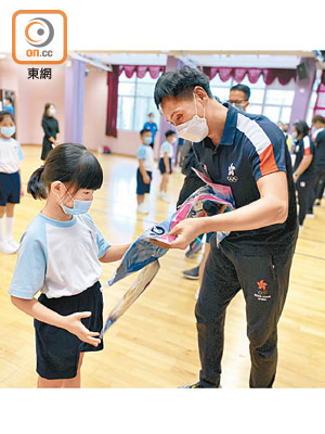 體育節大使鄧漢昇（右）派發禮物給小學生。