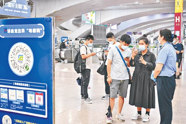 廣州南站旅客用手機掃健康碼。（中新社圖片）