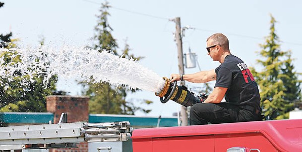 西雅圖以北的埃弗里特消防員開啟滅火水龍頭，替民眾降溫。