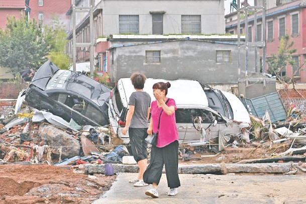 被洪水沖翻的車輛堆在一起。（中新社圖片）