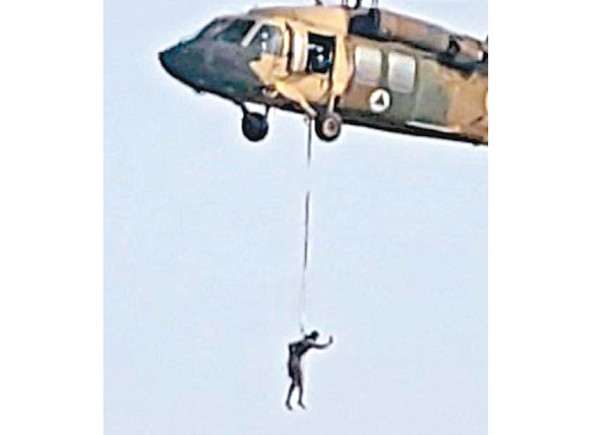 黑鷹直升機下方吊着一名人士飛行。
