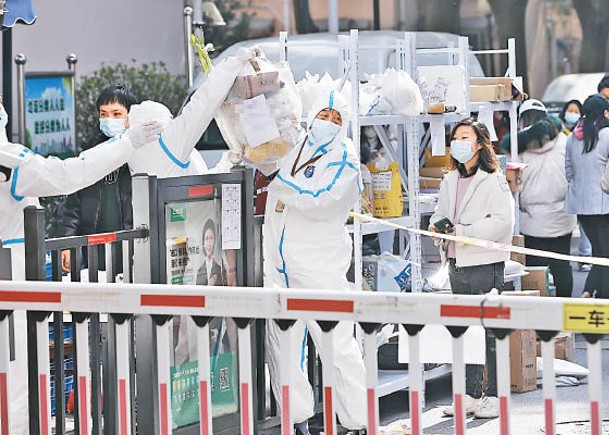 上海市工作人員在香樟苑小區門口傳遞居民的外賣物品。（中新社圖片）