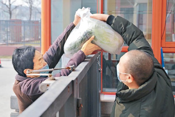 西安市小區居民接過配送的蔬菜。（中新社圖片）