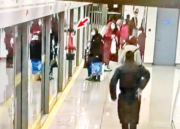 女乘客（箭嘴示）被月台幕門夾住。