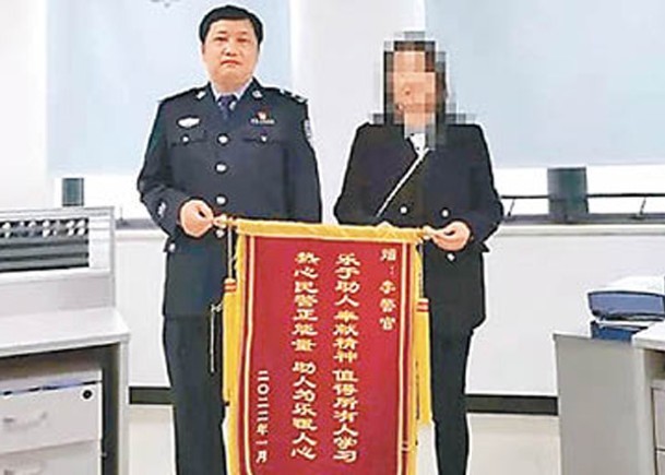 少年的母親向隊長李偉（左）送上錦旗表謝意。