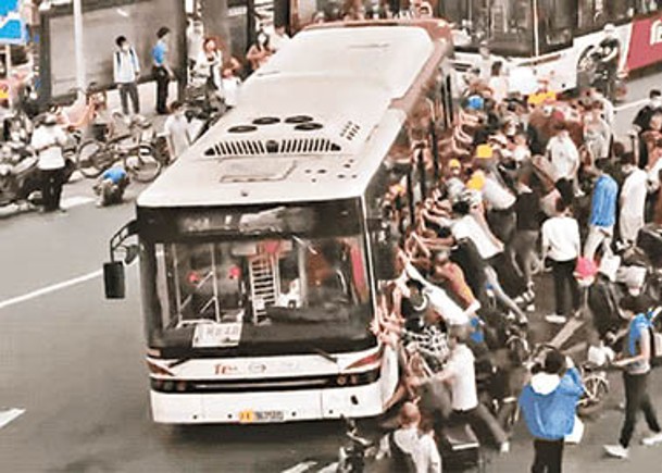 大批民眾合力抬起巴士救人。