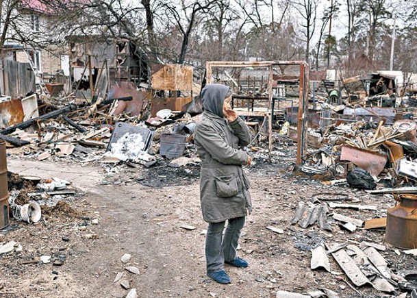 布恰居民站在受損的建築物前，神情哀傷。（Getty Images圖片）