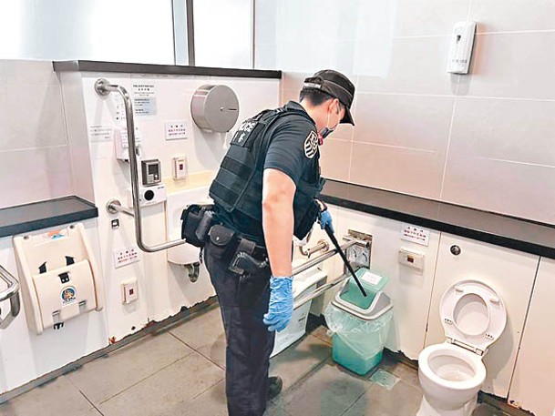 鐵路警察以金屬探測器檢視站區廁所。