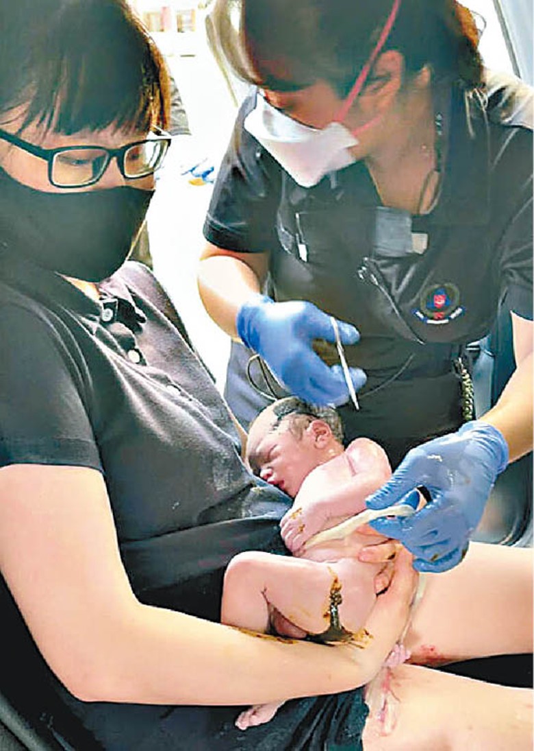 救護員為男嬰剪臍帶。