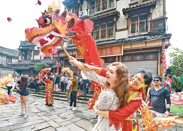 重慶的外籍留學生（左）體驗舞龍。（中新社圖片）