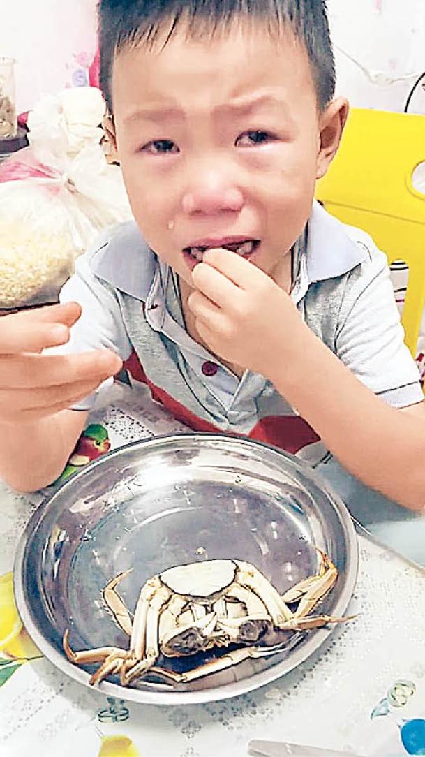 另一童邊哭邊吃大閘蟹。