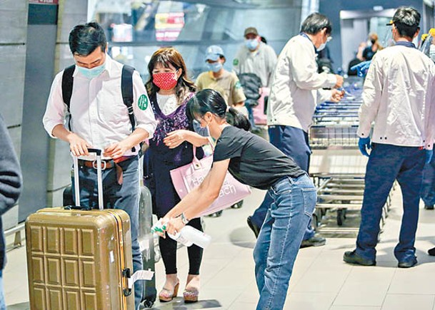 桃園機場職員為旅客的行李噴上消毒藥水。（中時電子報圖片）