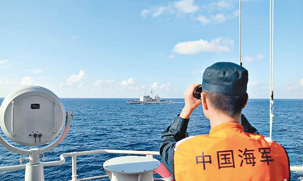 中國海軍士兵用望遠鏡監視美軍艦艇。