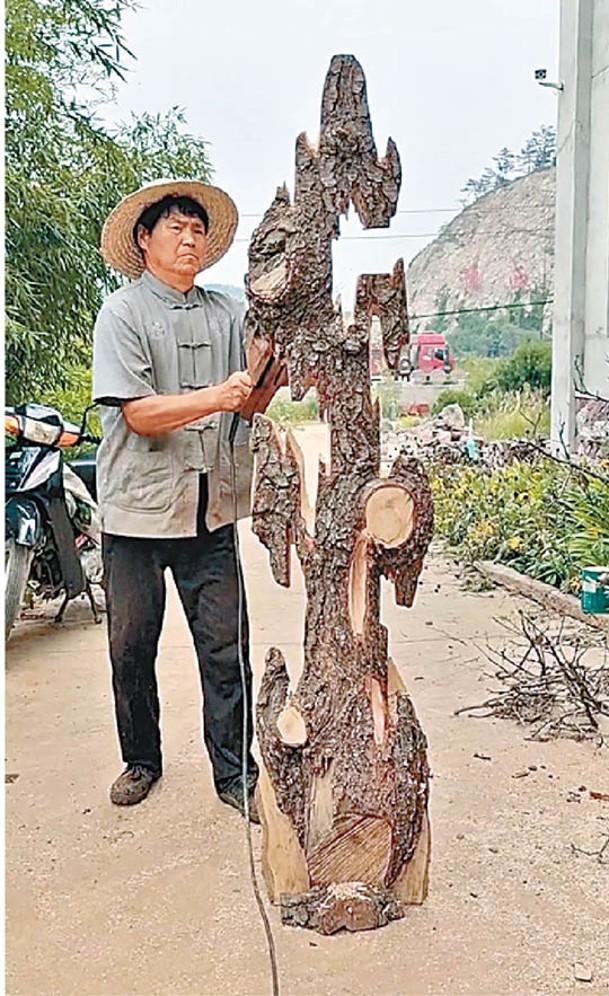 駱彥紅在山中採集材料雕製藝術品。