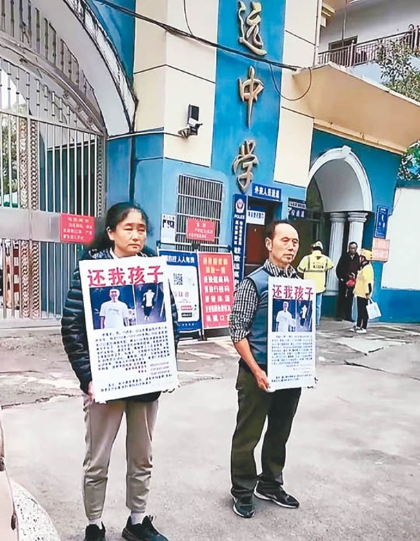 胡鑫宇的父母在校門口手持啟事尋子。