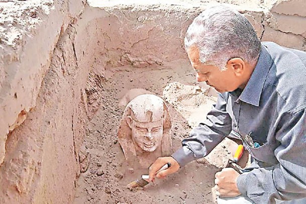 考古學家檢查出土雕像。