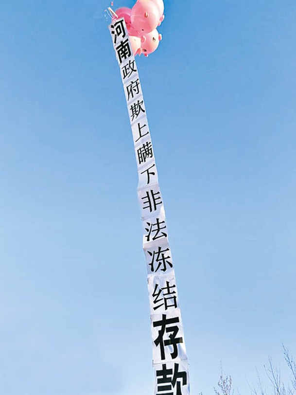 氣球懸掛印上「河南政府欺上瞞下非法凍結存款」的布條。