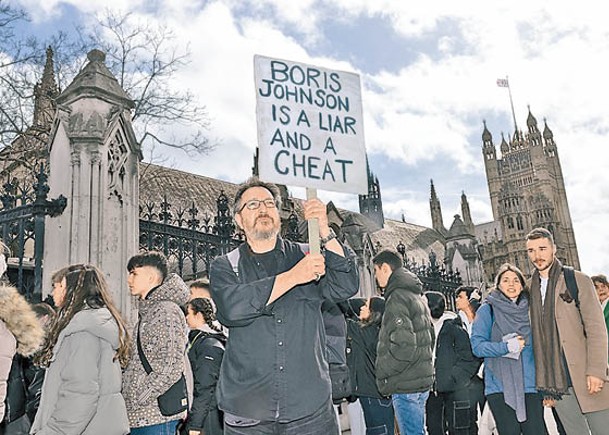 反對約翰遜人士在西敏宮外舉牌抗議。（Getty Images圖片）