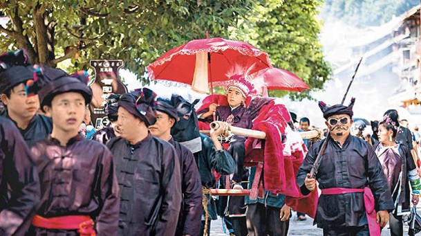 村民抬着轎子上的「官人」繞寨巡遊。