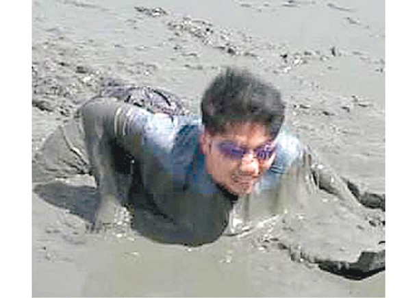 學生在泥灘中滑行。